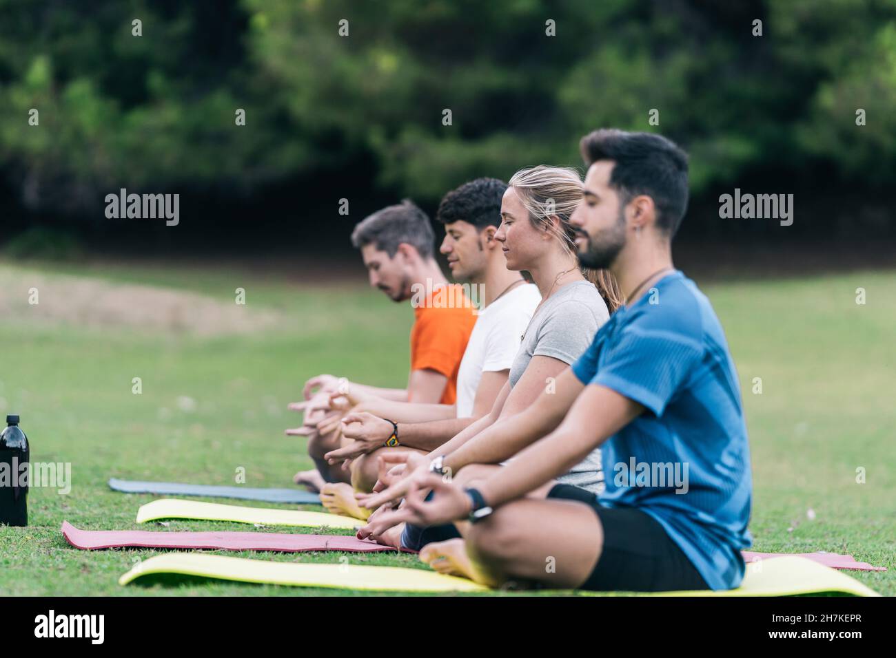 Gruppo di quattro persone che fanno la posa di loto di yoga in un parco Foto Stock