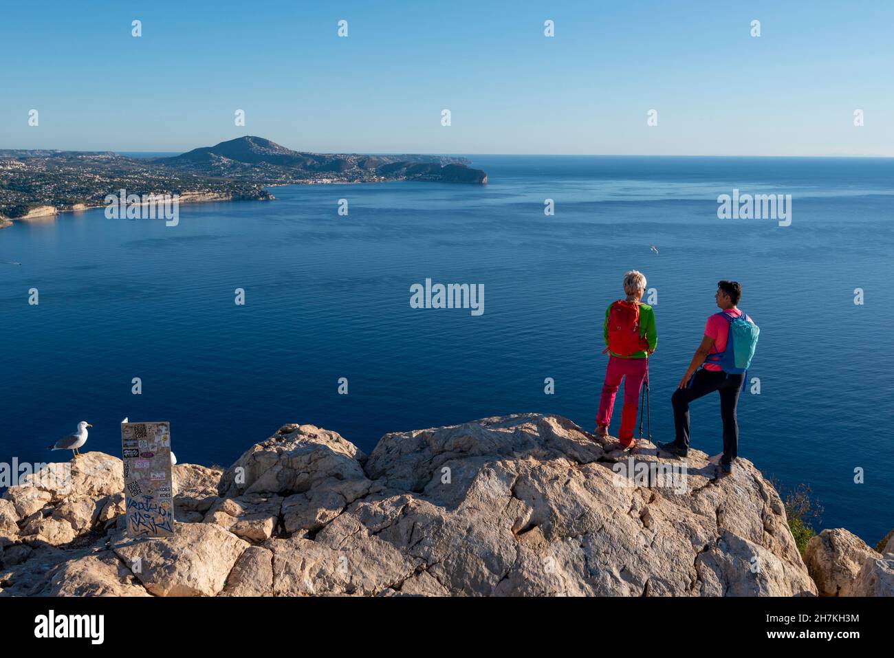 Due escursionisti si levano in piedi sul pinnacolo sopra il mare e le colline del mediterraneo e guardano fuori, Calpe, provincia di Alicante, Spagna Foto Stock