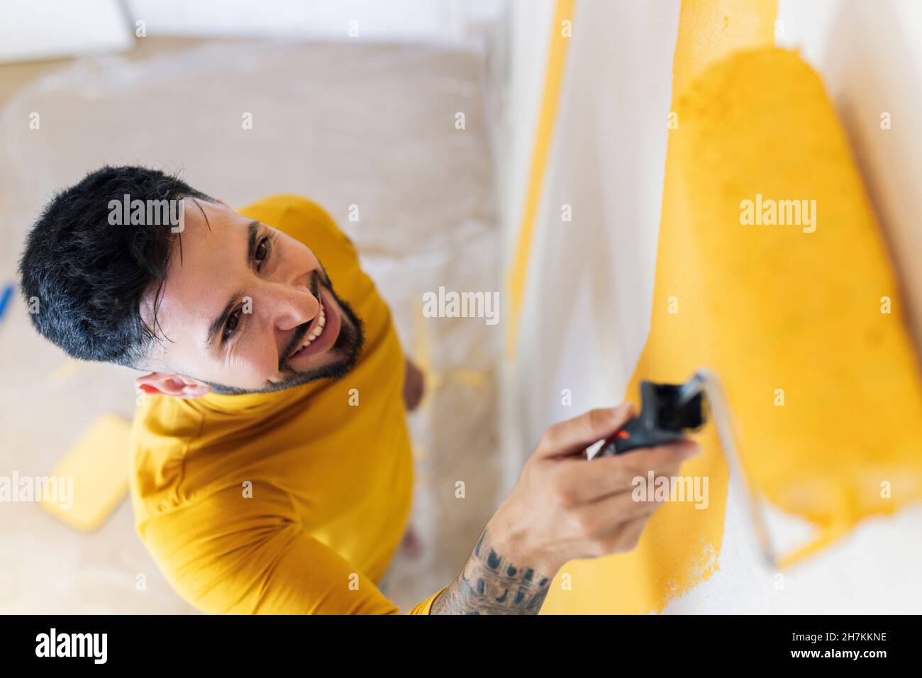 Uomo adulto medio parete di pittura con rullo di vernice a casa Foto Stock