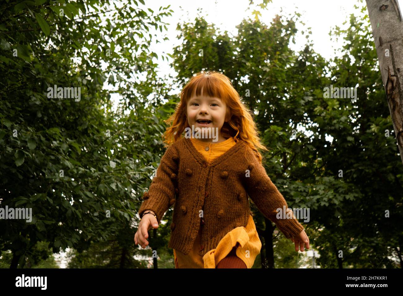 Sorridente ragazza rossa che corre nel parco Foto Stock