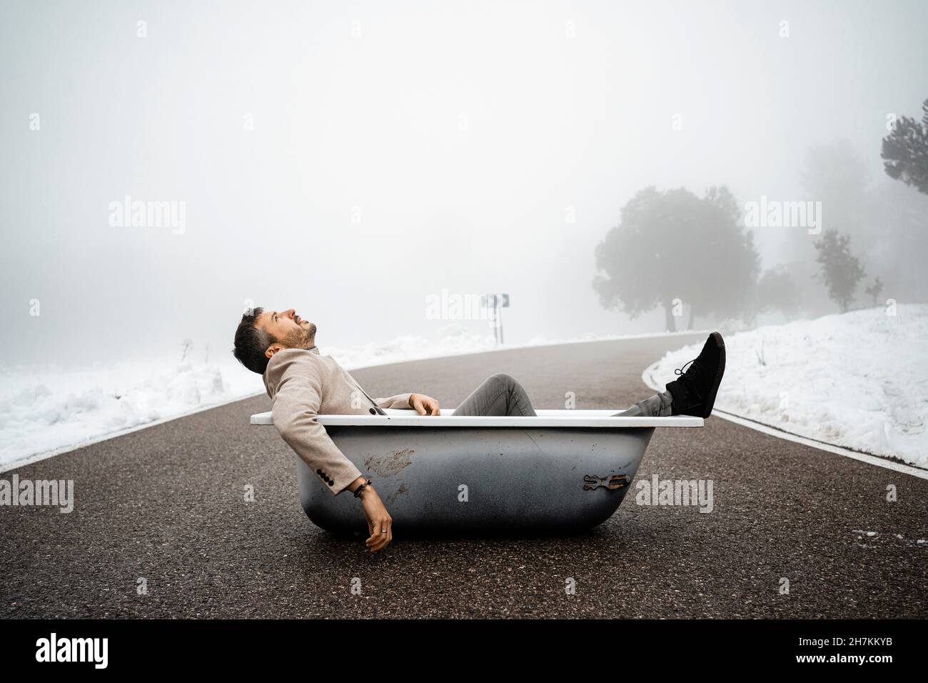 Uomo stanco che si rilassa nella vasca da bagno sulla strada Foto Stock