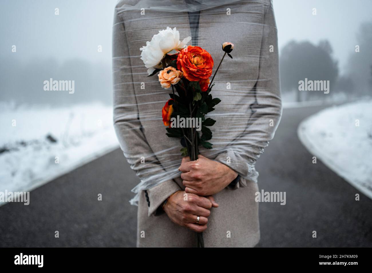Uomo in plastica che tiene fiori durante l'inverno Foto Stock
