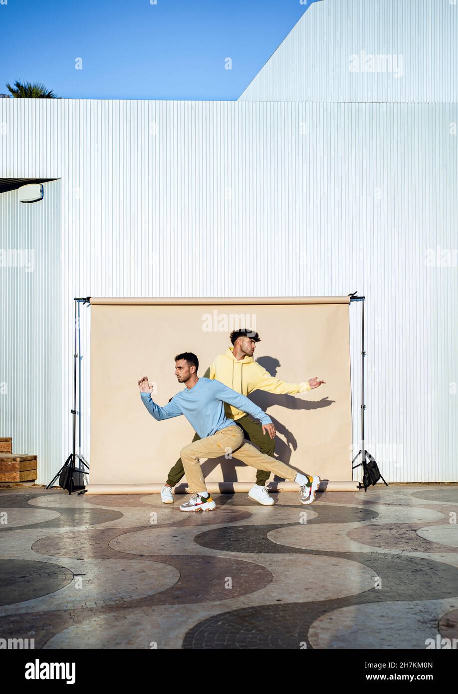 Amici maschi che ballano di fronte allo sfondo Foto Stock