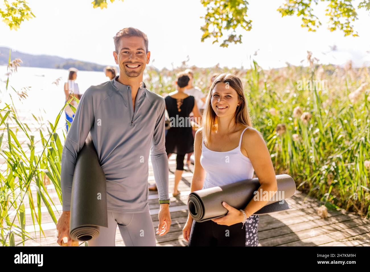 Uomo e donna in piedi con materassini da ginnastica alla classe yoga Foto Stock