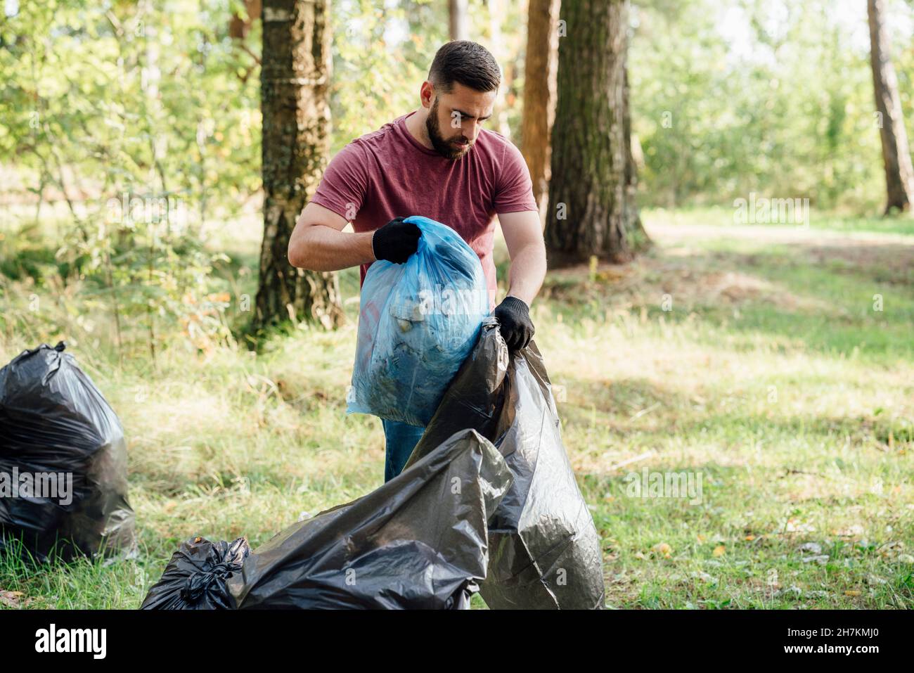 Volontario maschile che mette rifiuti in sacco rifiuti Foto Stock