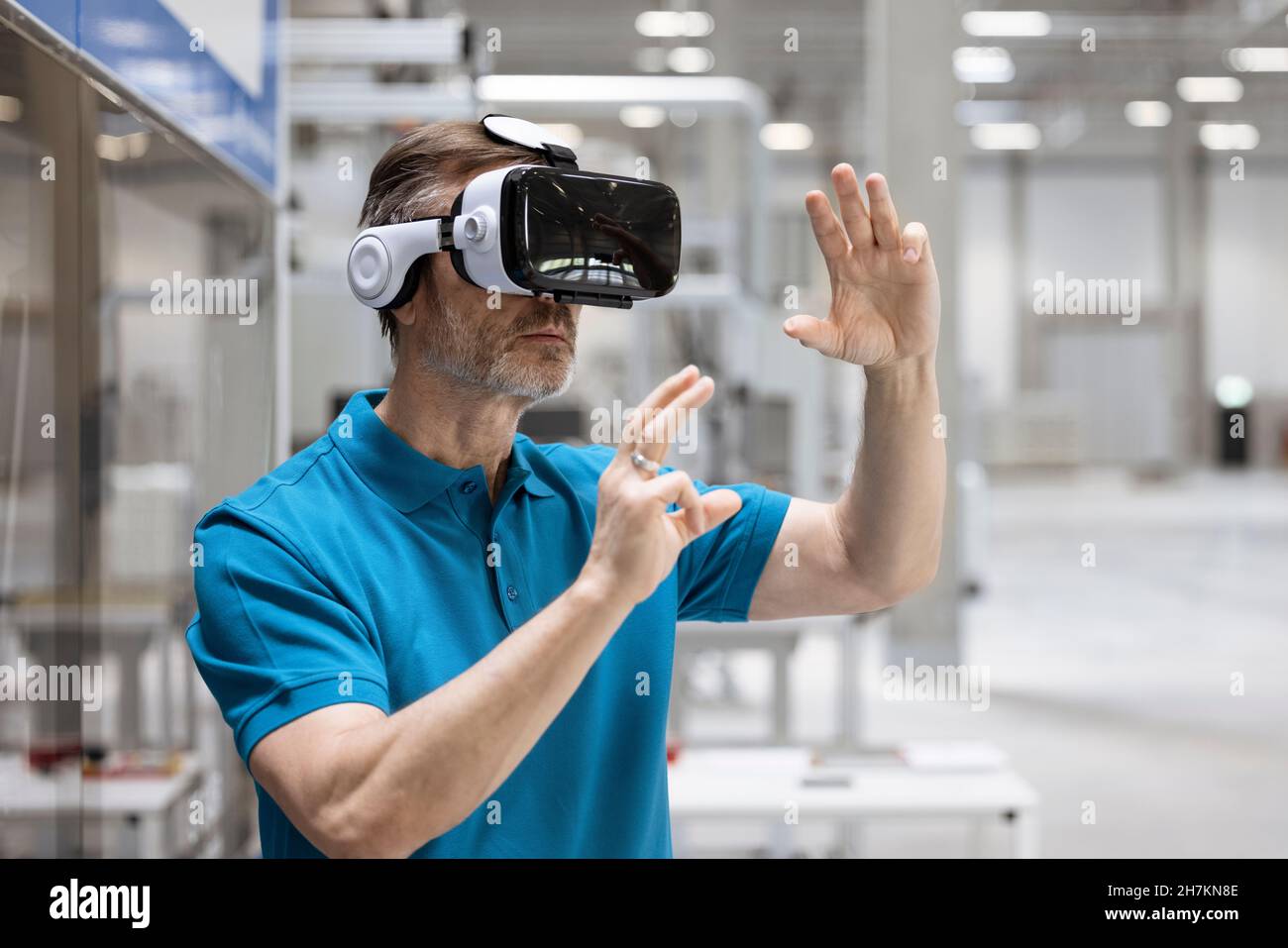 Uomo sorridente con le braccia incrociate appoggiate sul vetro nell'industria Foto Stock