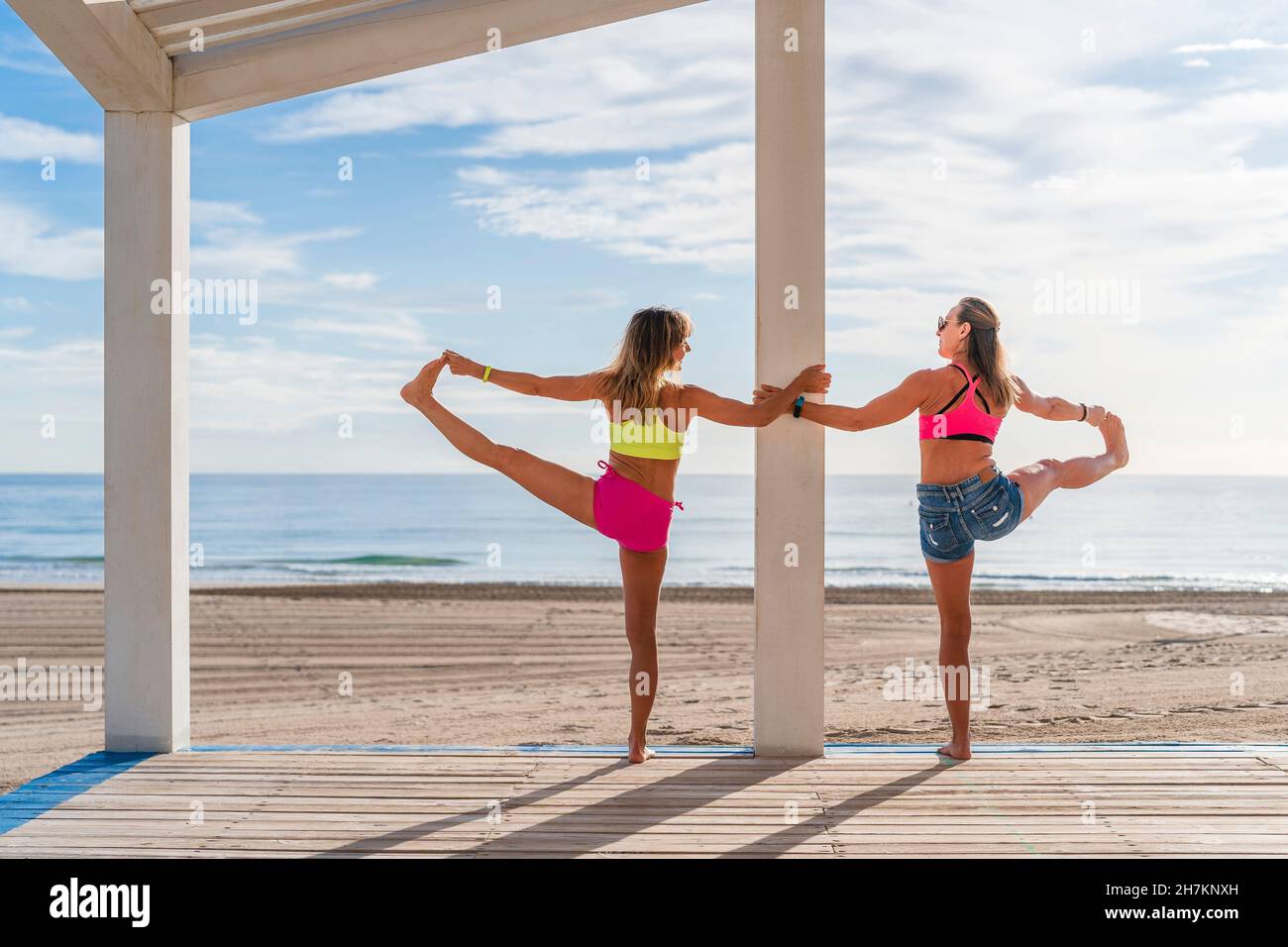 Sportivi maturi in equilibrio su una gamba mentre praticano in spiaggia Foto Stock