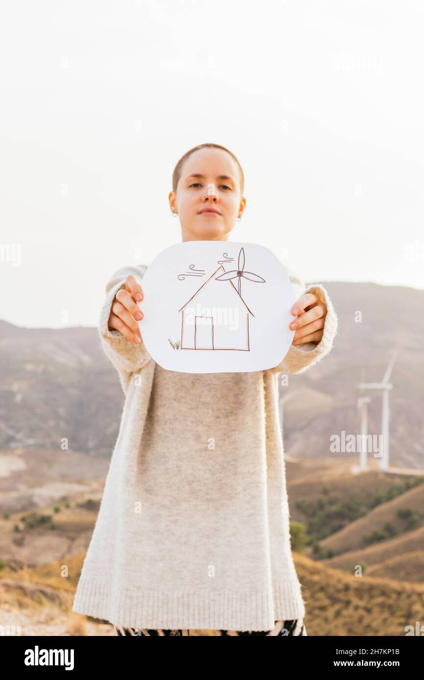Donna che tiene carta con disegno di casa mentre si alza in montagna Foto Stock