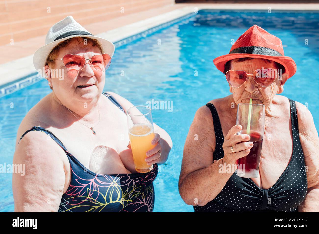 Le amiche anziane hanno succo in piscina durante l'estate Foto Stock