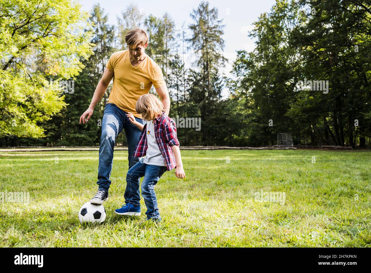 Padre e figlio giocano con la palla di calcio al parco Foto Stock