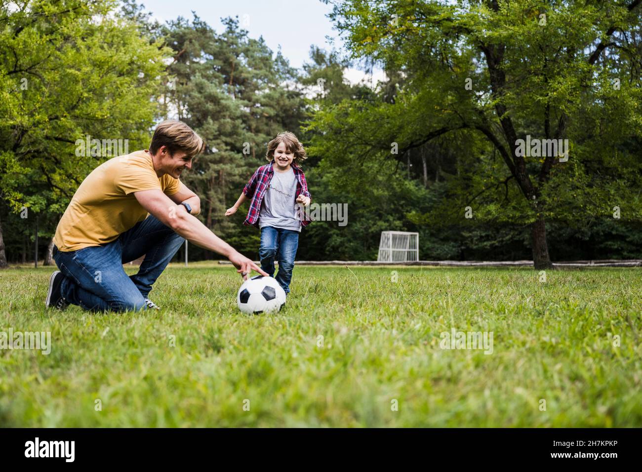 La famiglia gioca con la palla di calcio sull'erba Foto Stock