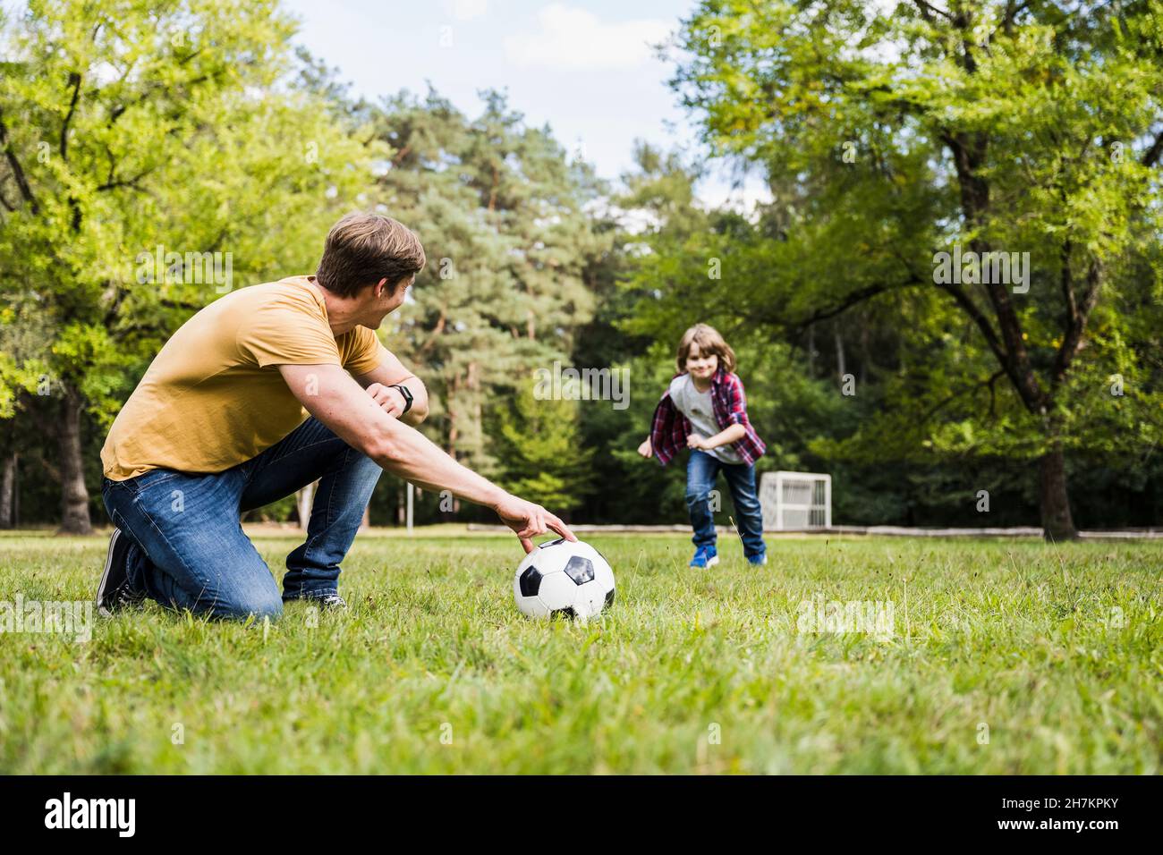 Uomo e ragazzo che giocano con la palla di calcio sull'erba Foto Stock