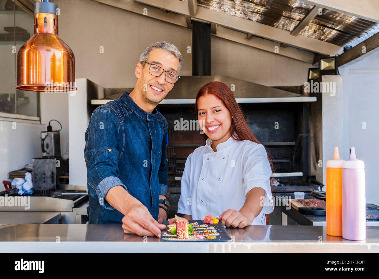 Chef sorridenti di sesso maschile e femminile con vassoio al ristorante Foto Stock