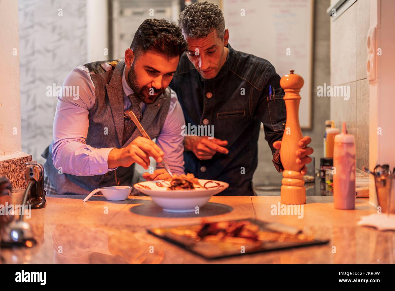 Chef maschili che guarniscono il cibo nel ristorante Foto Stock
