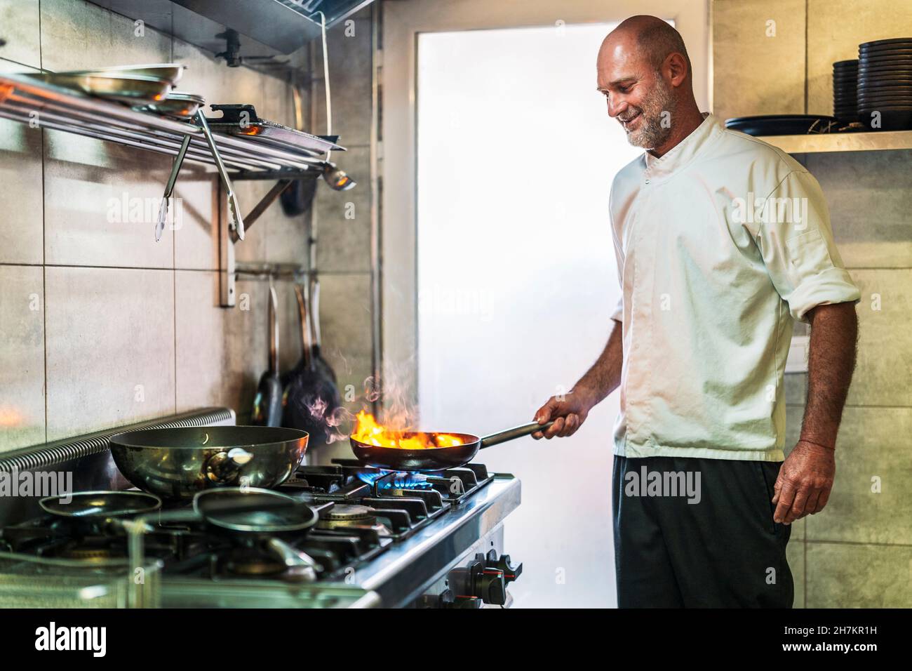 Chef maschile sorridente che cucinava al ristorante Foto Stock