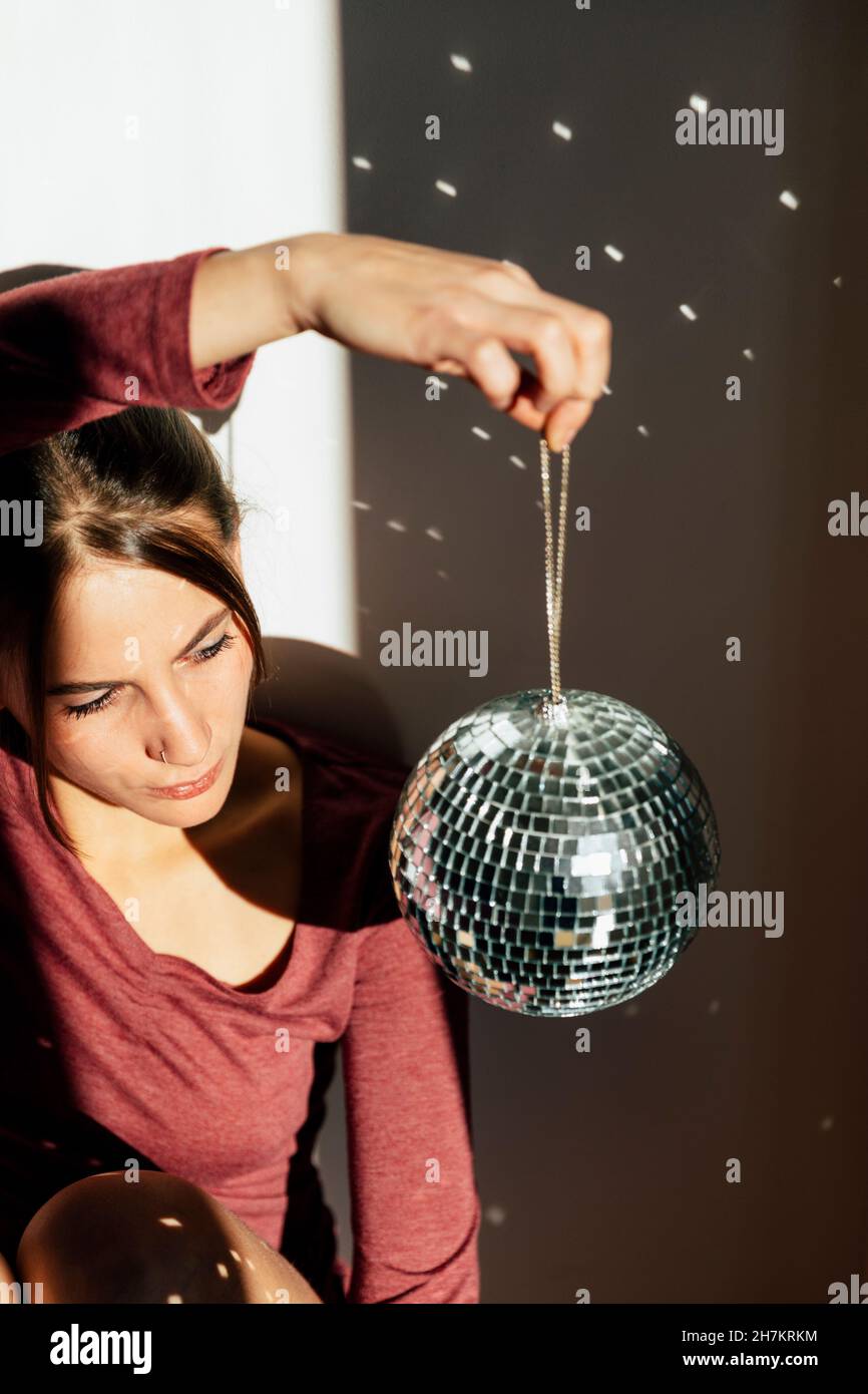 Ragazza depressa che guarda la sfera della discoteca mentre si siede a casa Foto Stock