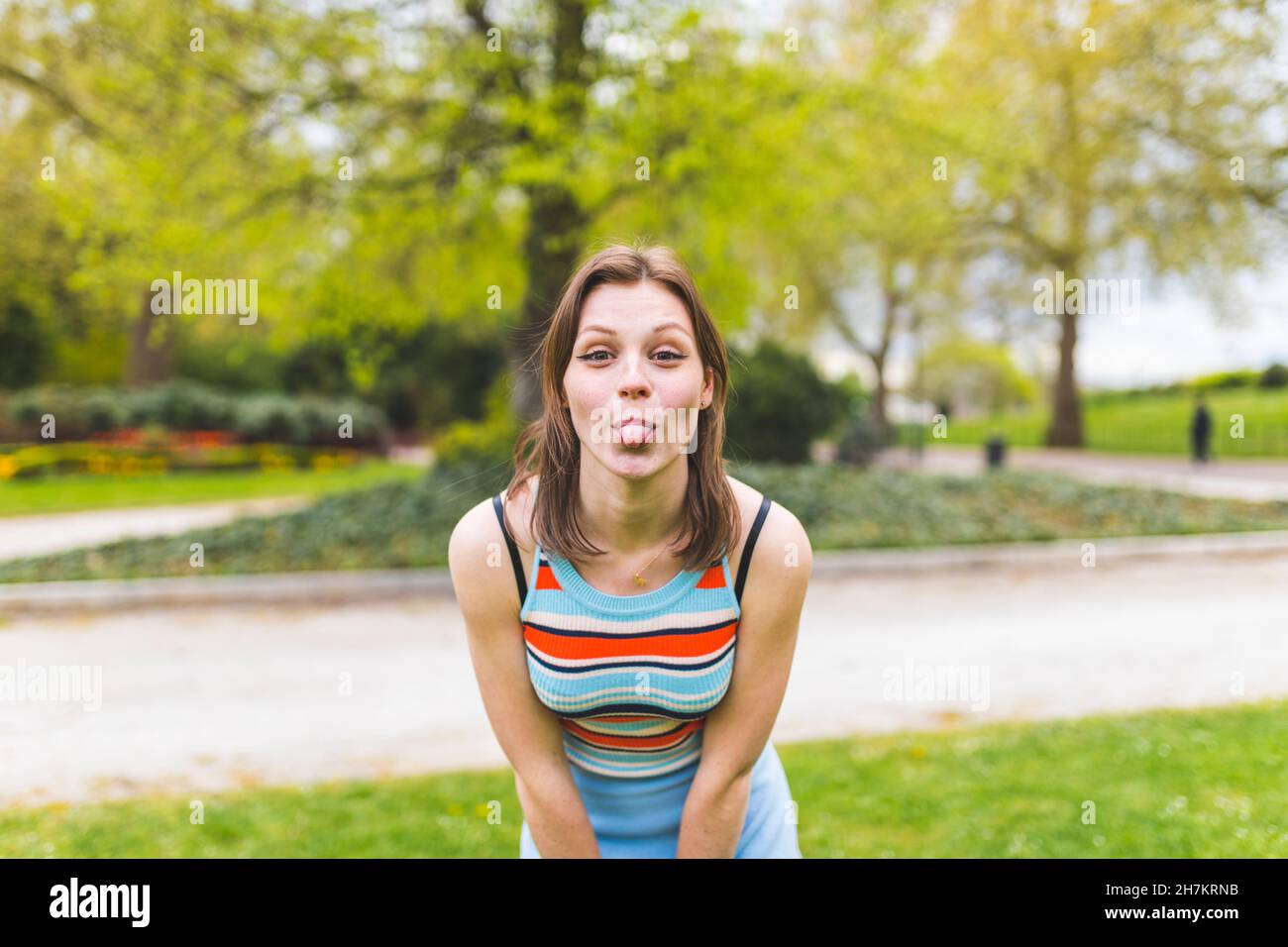 Donna giocosa che attacca la lingua al parco pubblico Foto Stock