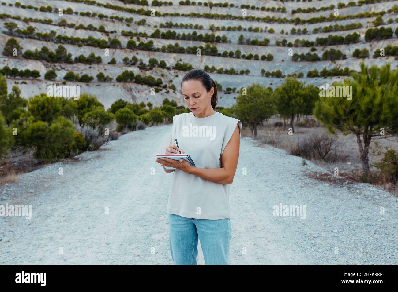 Scienziato femminile iscritto nel libro mentre in piedi nella vecchia mia Foto Stock