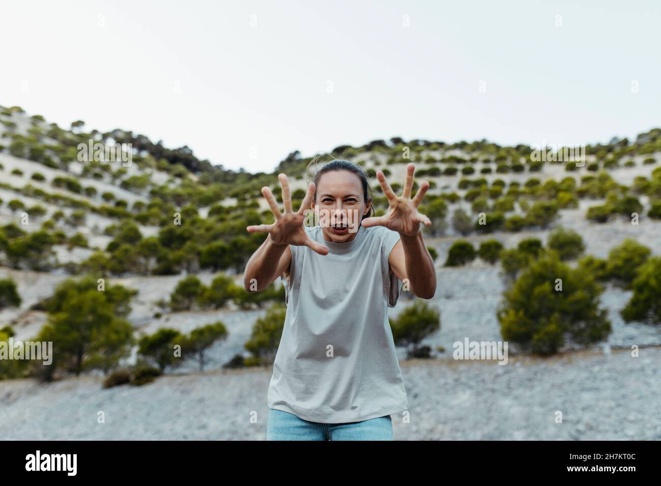 Donna gesturing mentre facendo faccia divertente al campo Foto Stock