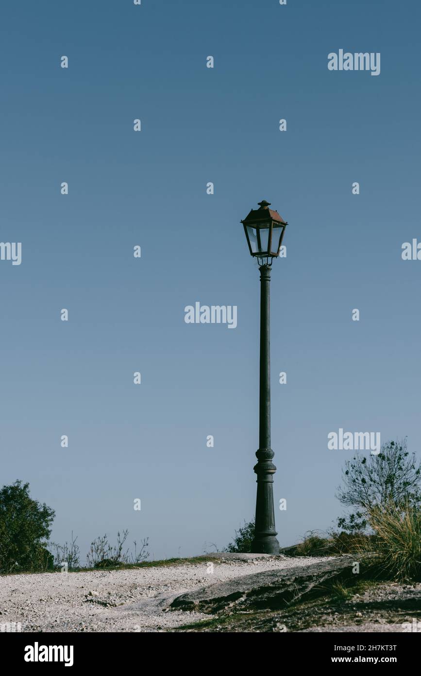 Scatto verticale di una lampada da strada o di una lanterna con un palo alto contro il cielo azzurro chiaro Foto Stock