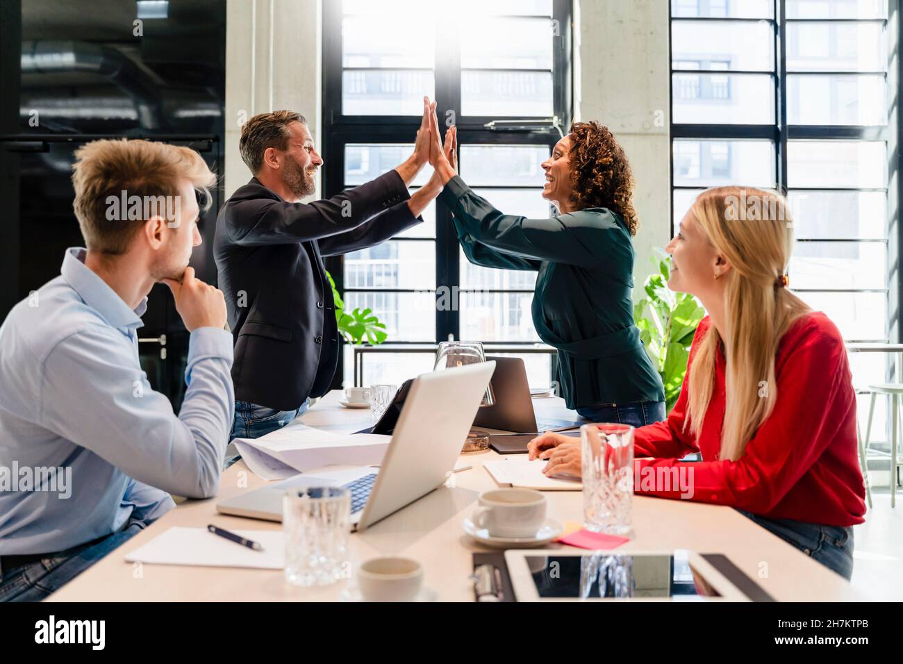 I colleghi che si acclamano durante la riunione in ufficio Foto Stock