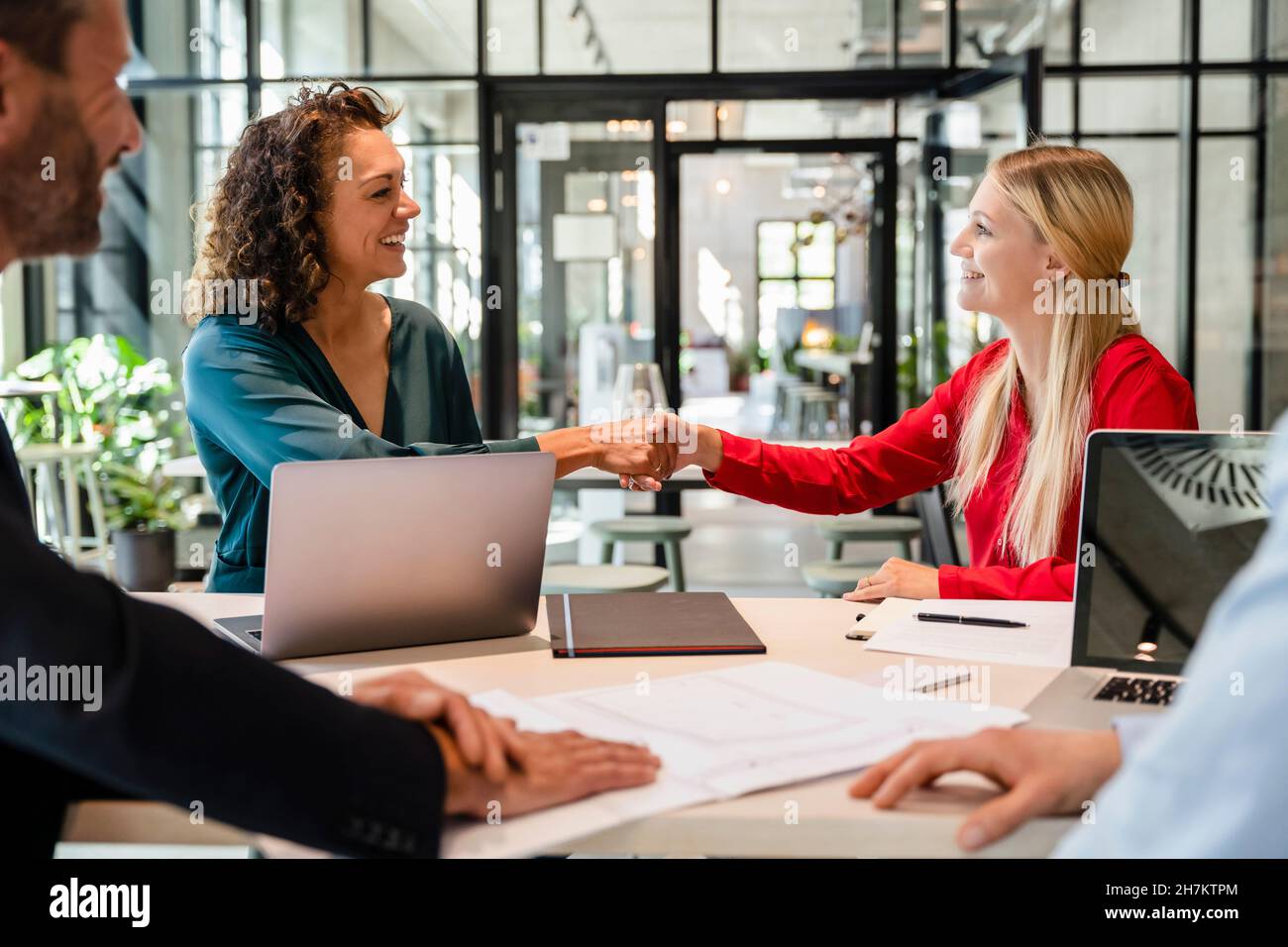 Donne d'affari che fanno la stretta di mano in riunione all'ufficio Foto Stock