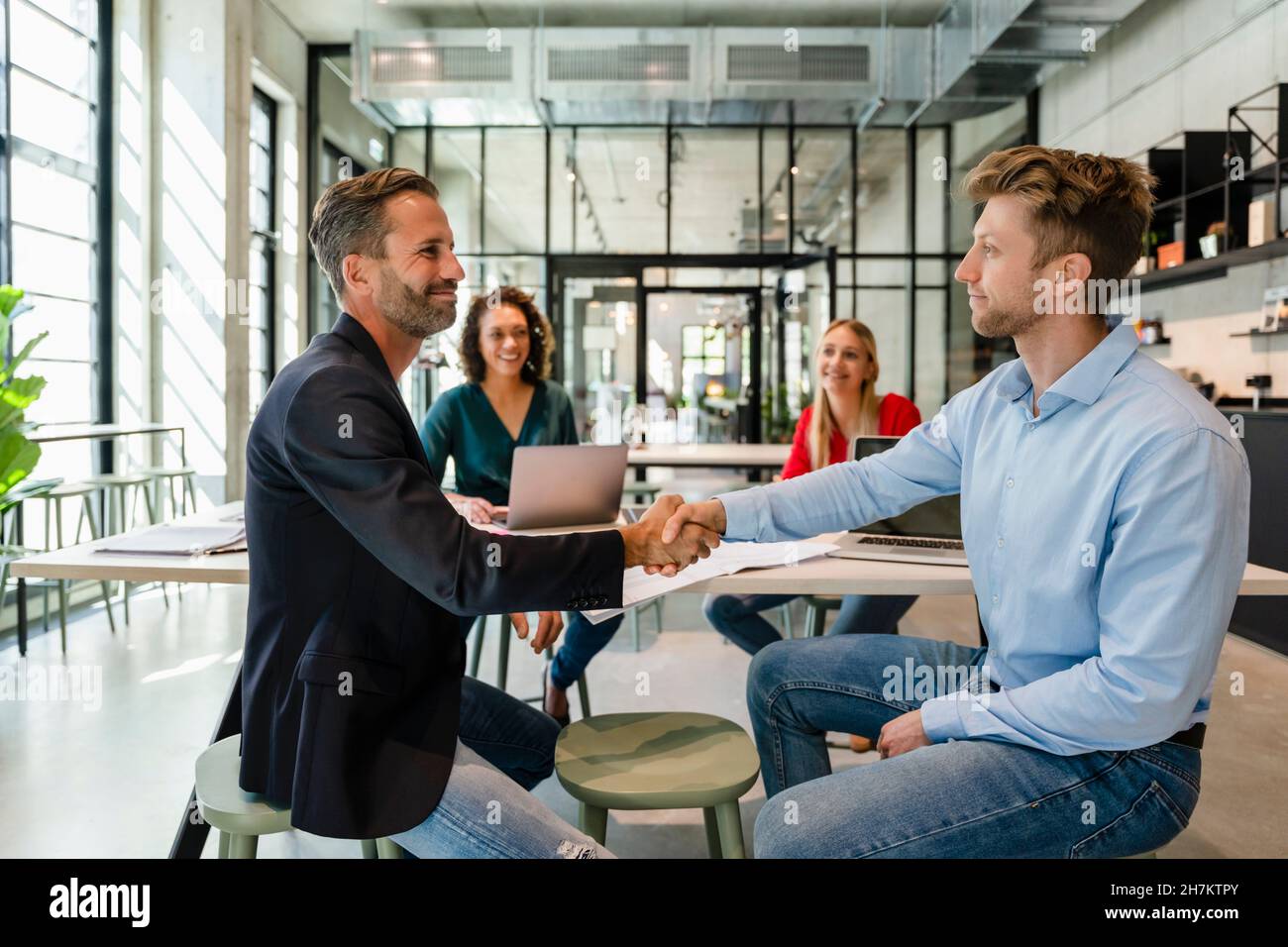 Uomini d'affari che fanno una stretta di mano nell'incontro con i colleghi in ufficio Foto Stock
