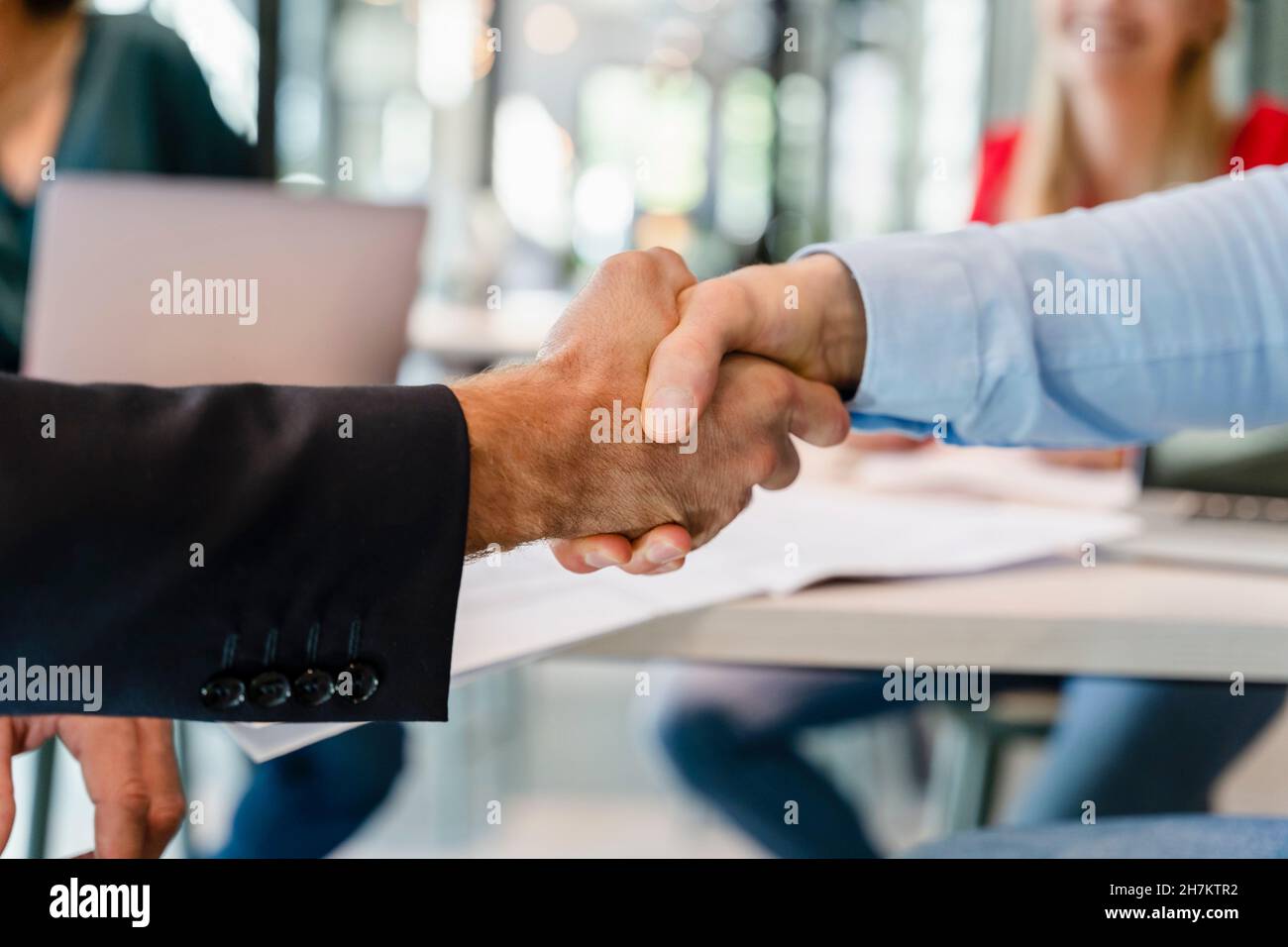 Uomini d'affari che fanno stretta di mano in riunione in ufficio Foto Stock