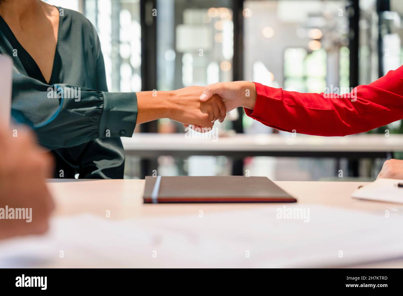 Donne d'affari che fanno la stretta di mano alla scrivania Foto Stock