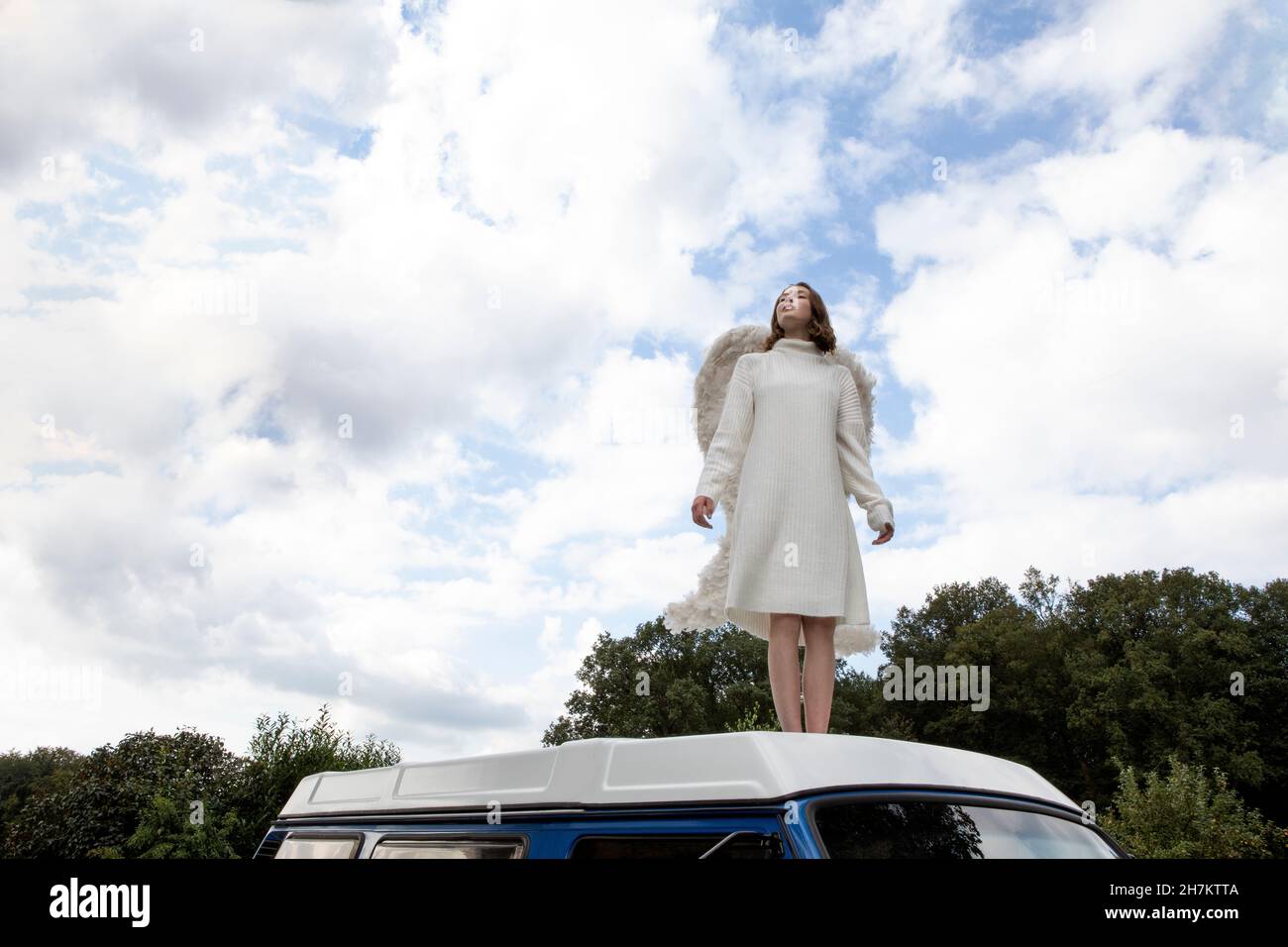 Ragazza adolescente che indossa costume angelo sul tetto del furgone Foto Stock