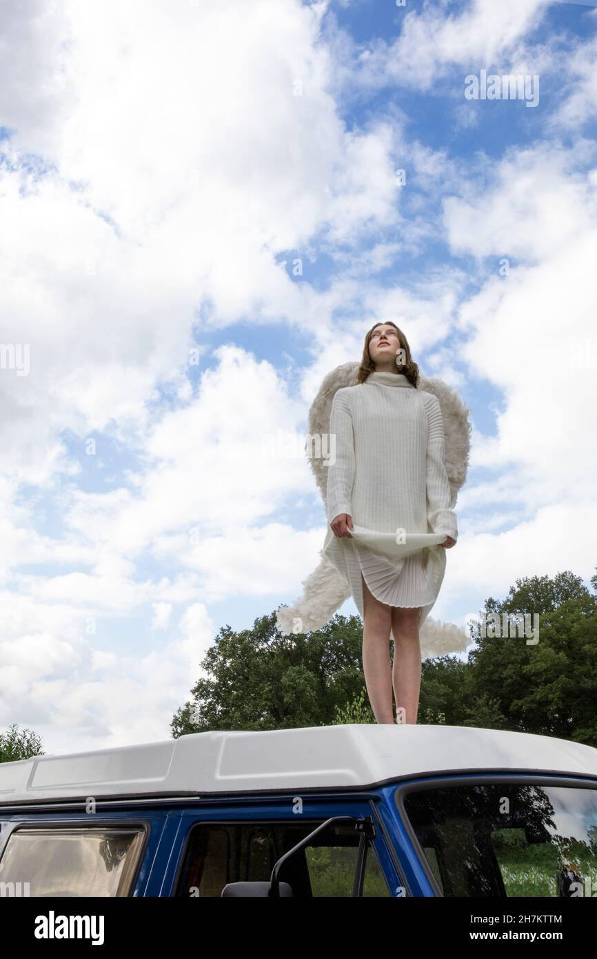 Ragazza adolescente in costume angelo sul tetto del furgone Foto Stock
