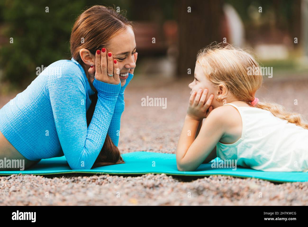 Sorridendo la madre e la figlia che si guardano mentre si stendono sul tappeto da sforzo Foto Stock