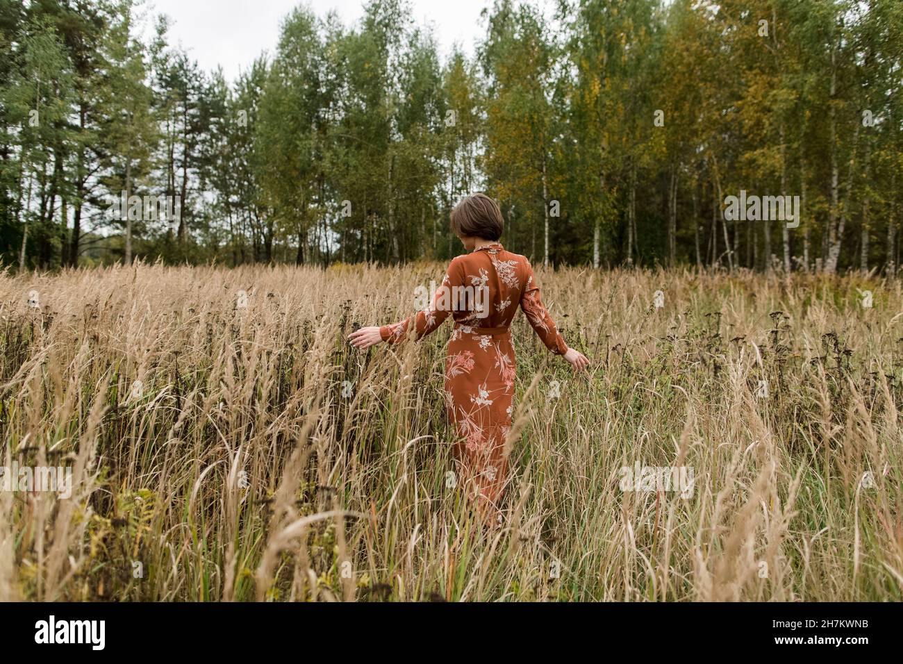 Donna vestito camminare tra raccolti sul campo Foto Stock