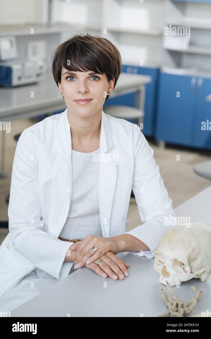 Scienziato con modello anatomico del cranio umano alla scrivania Foto Stock