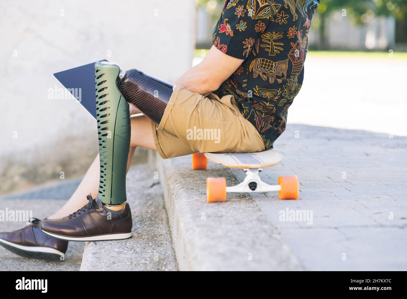 Uomo disabili sorridente con capelli lunghi utilizzando un computer portatile nel parco pubblico Foto Stock