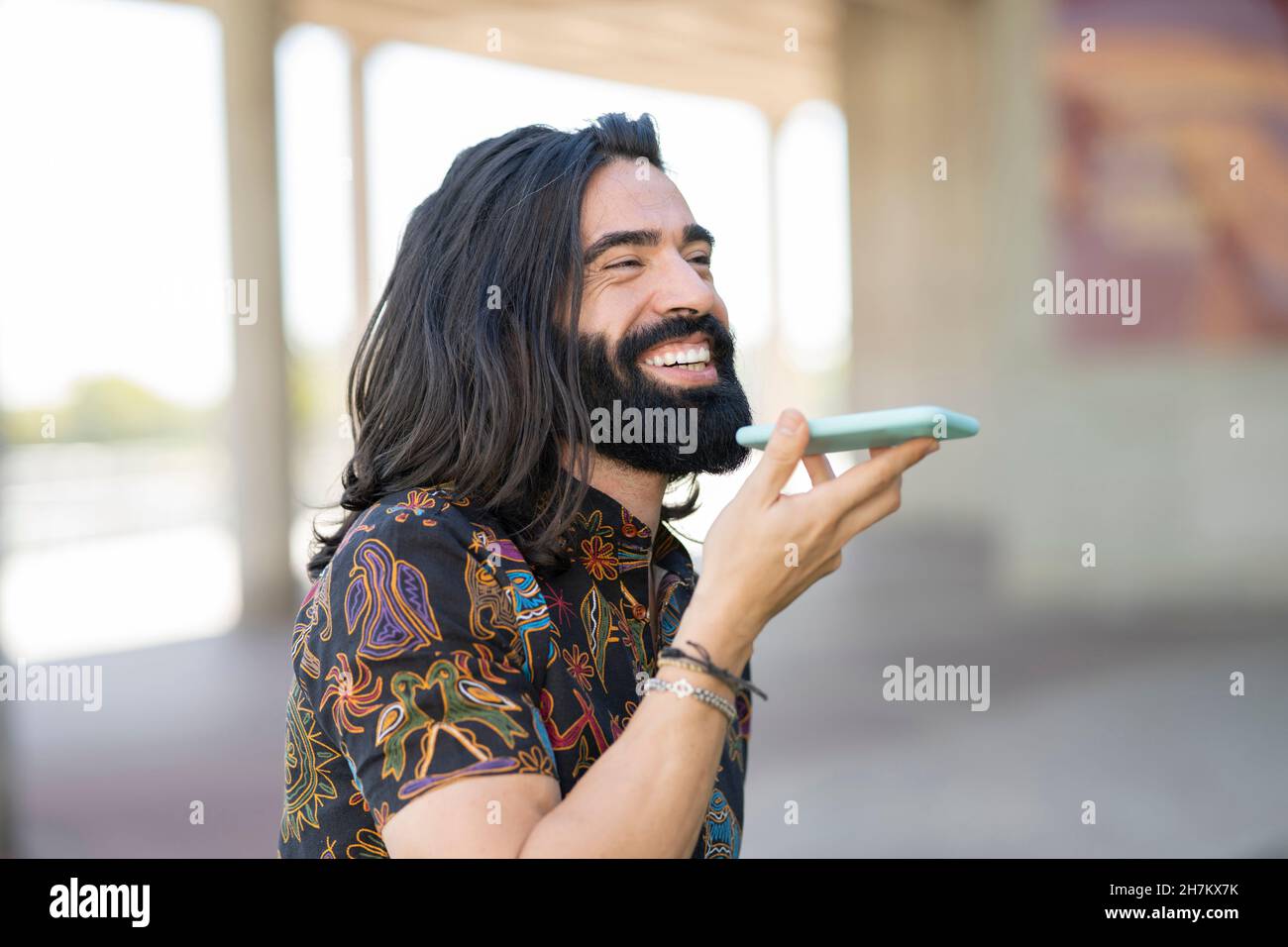 Happy hipster uomo con cuffie che tengono occhiali in parco Foto Stock