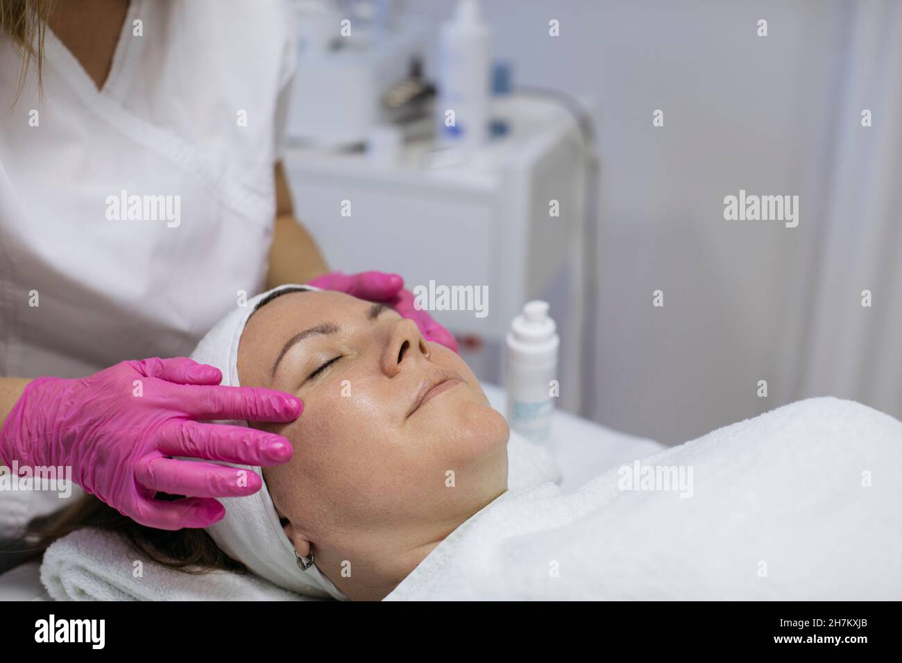 Beautician facendo massaggio viso di donna matura in salone Foto Stock