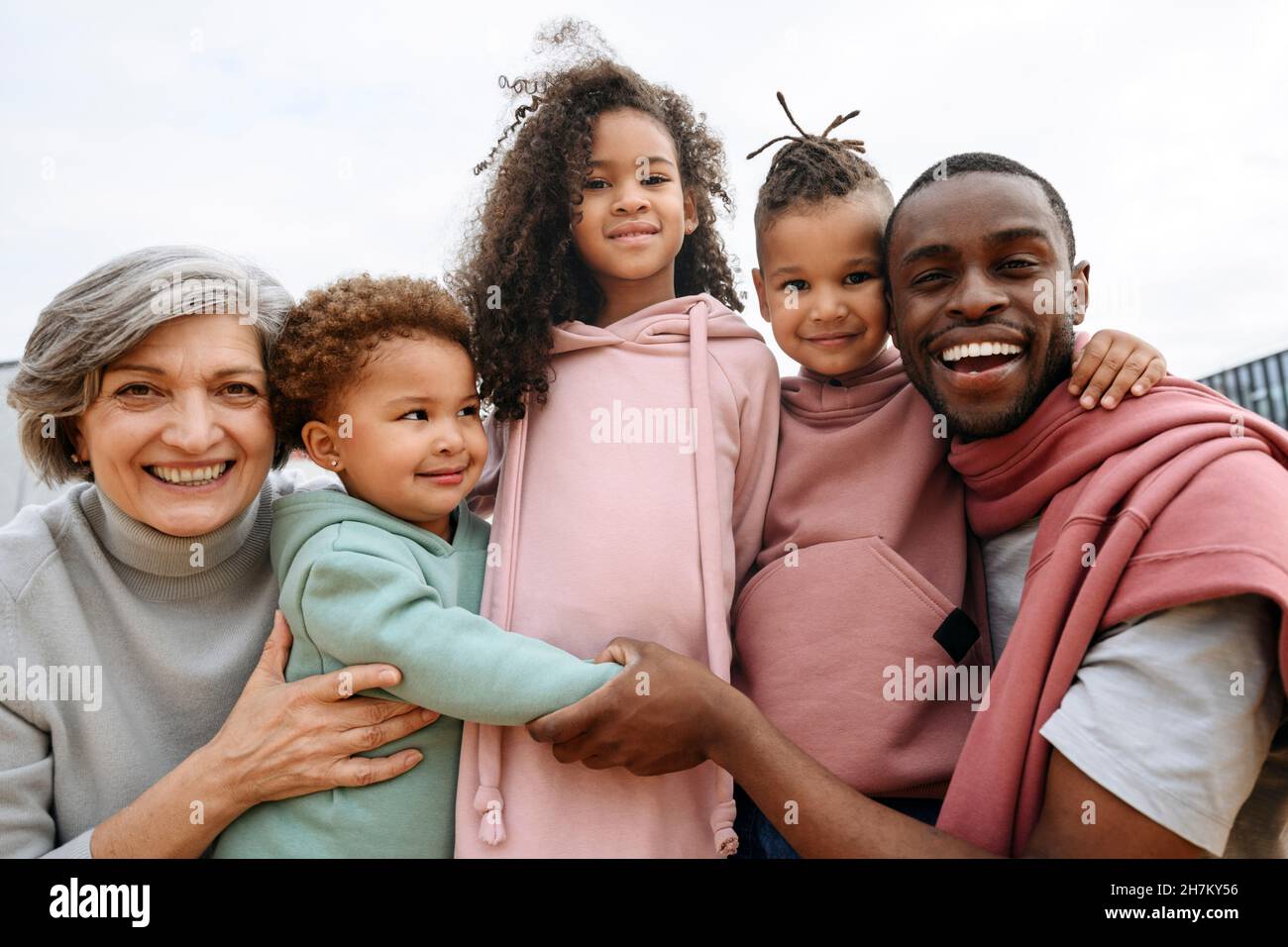 Sorridente padre che abbraccia la famiglia al campo sportivo Foto Stock