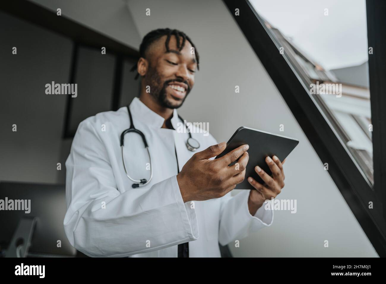 Medico sorridente che usa un tablet PC in ufficio Foto Stock