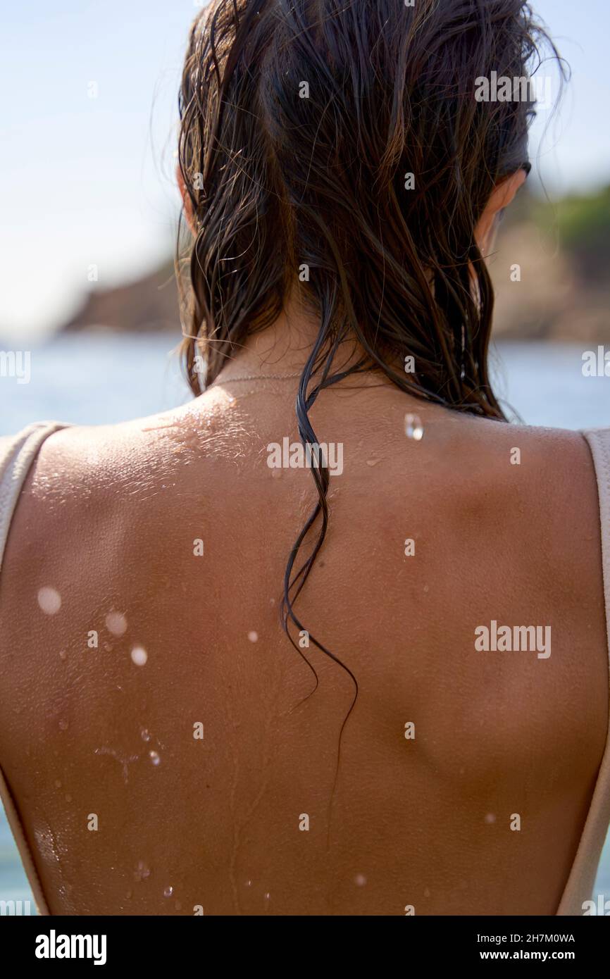 Giovane donna con capelli bagnati e schiena in spiaggia Foto Stock
