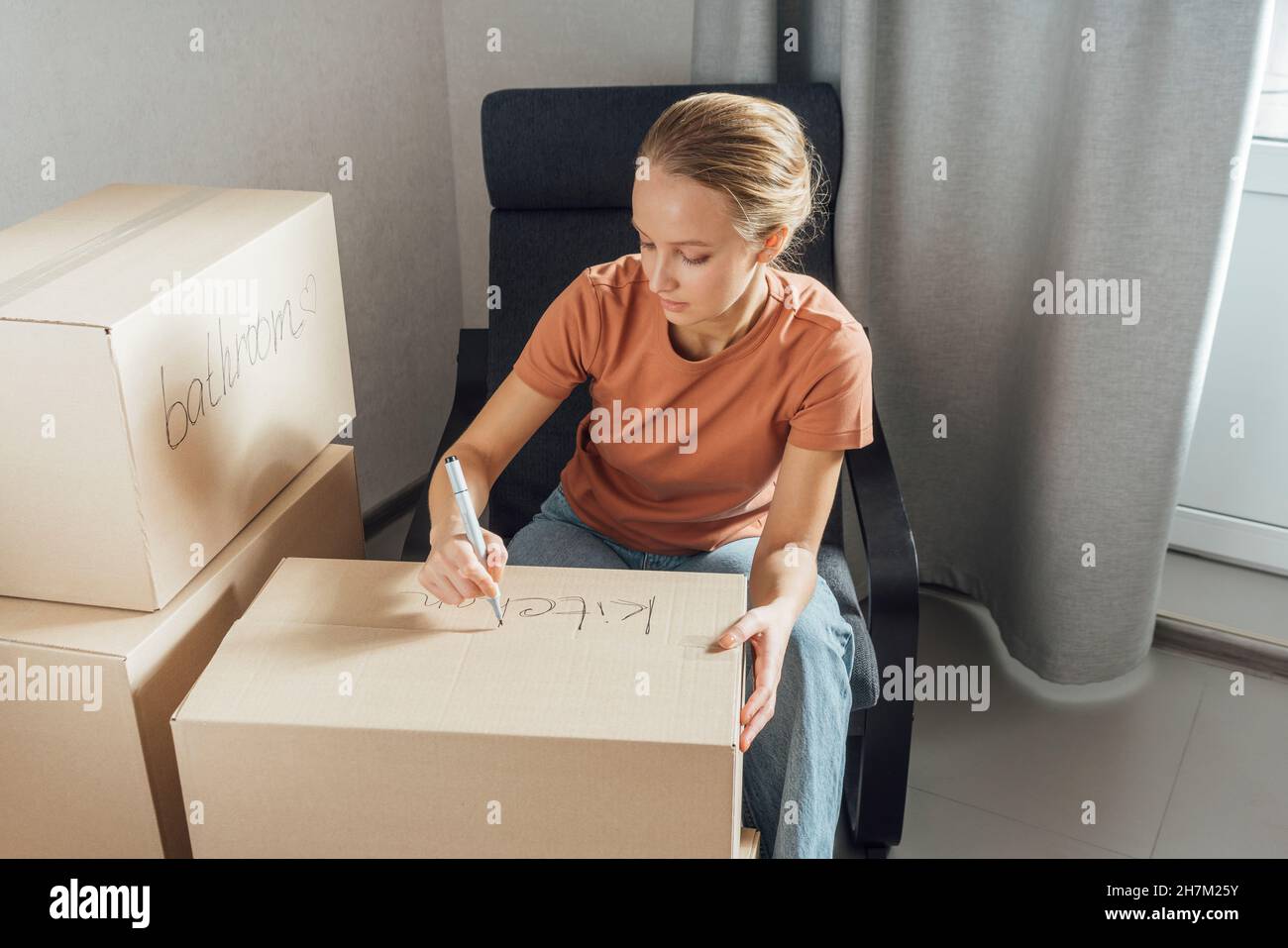 Donna che scrive con penna feltro sulla scatola di cartone a casa Foto Stock