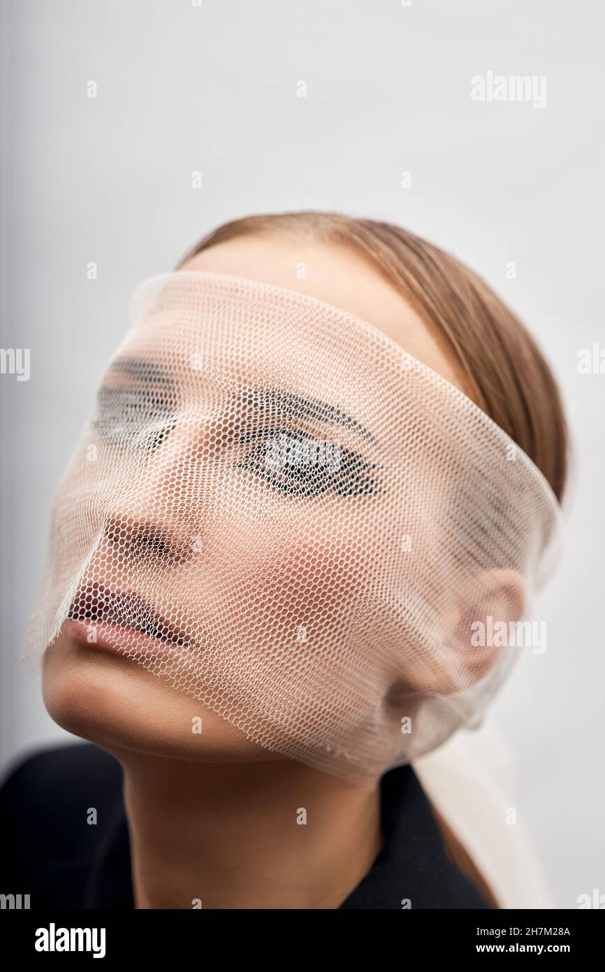 Giovane donna coperta di velo trasparente su sfondo bianco Foto Stock