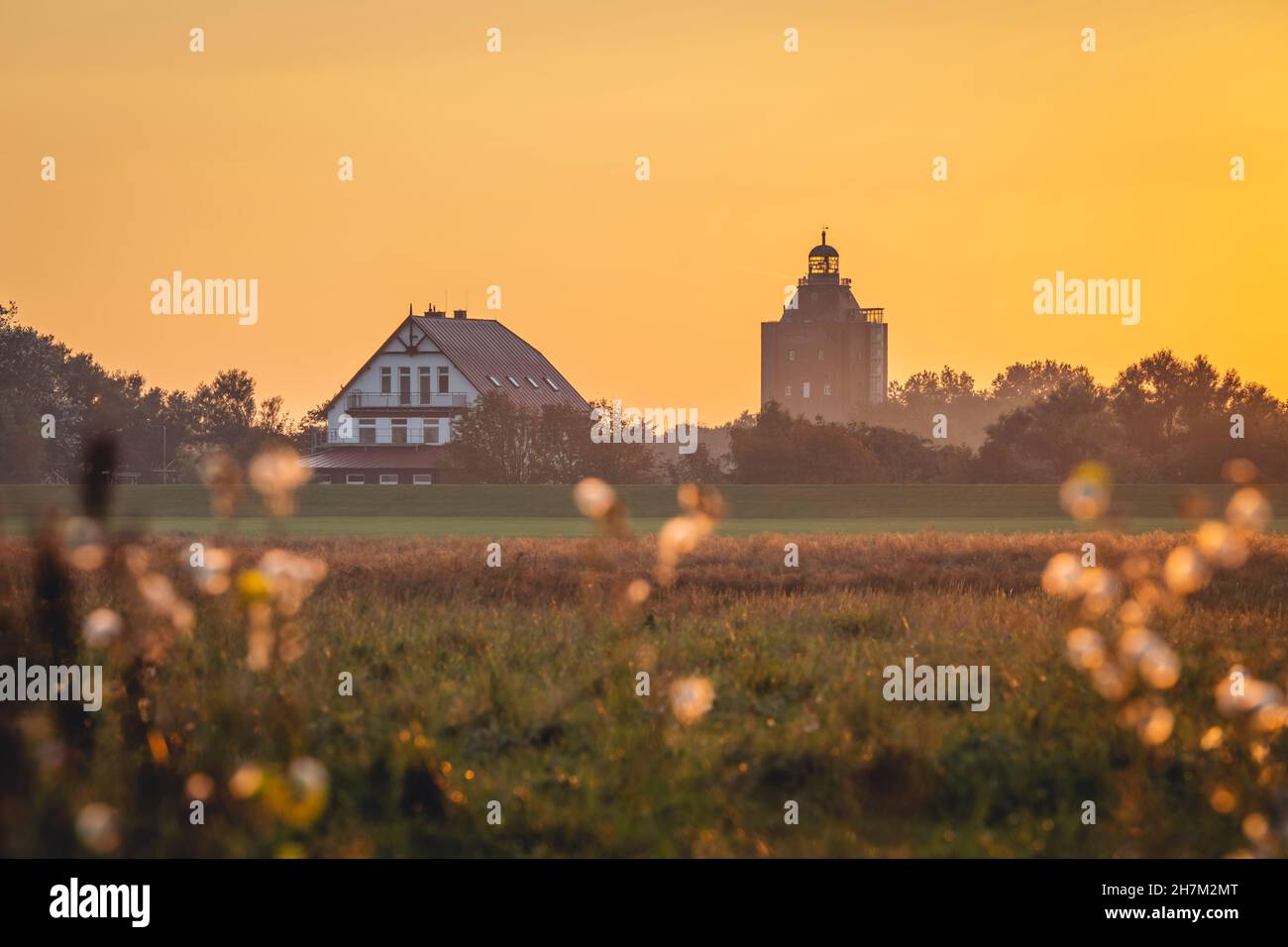 Germania, Amburgo, Villaggio sull'isola di Neuwerk al tramonto con la Grande Torre del Faro Neuwerk sullo sfondo Foto Stock