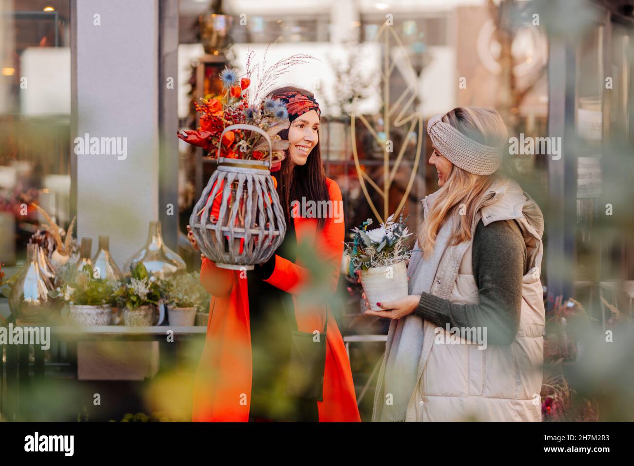 Amici con vasi di fiori che parlano fuori negozio Foto Stock