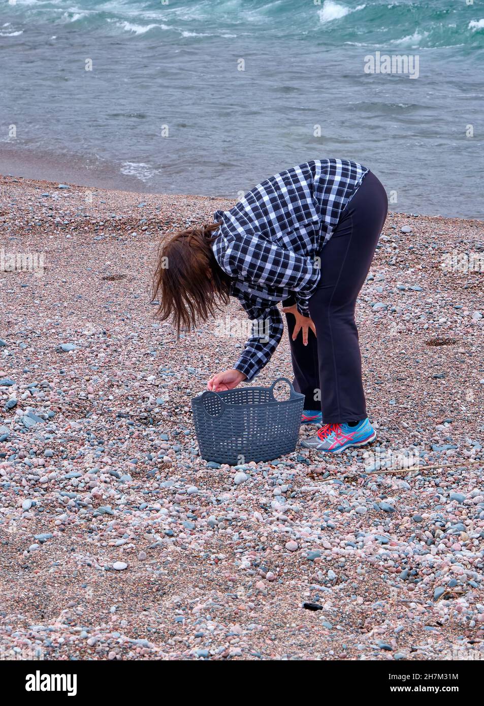 Donna raccoglie ciottoli e pietre sulla riva nord del lago superiore. Foto Stock