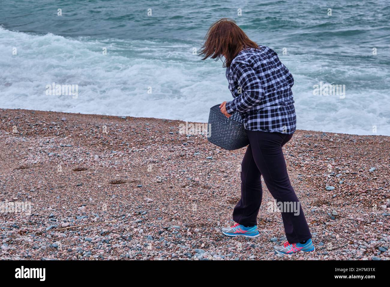Donna raccoglie ciottoli e pietre sulla riva nord del lago superiore. Foto Stock