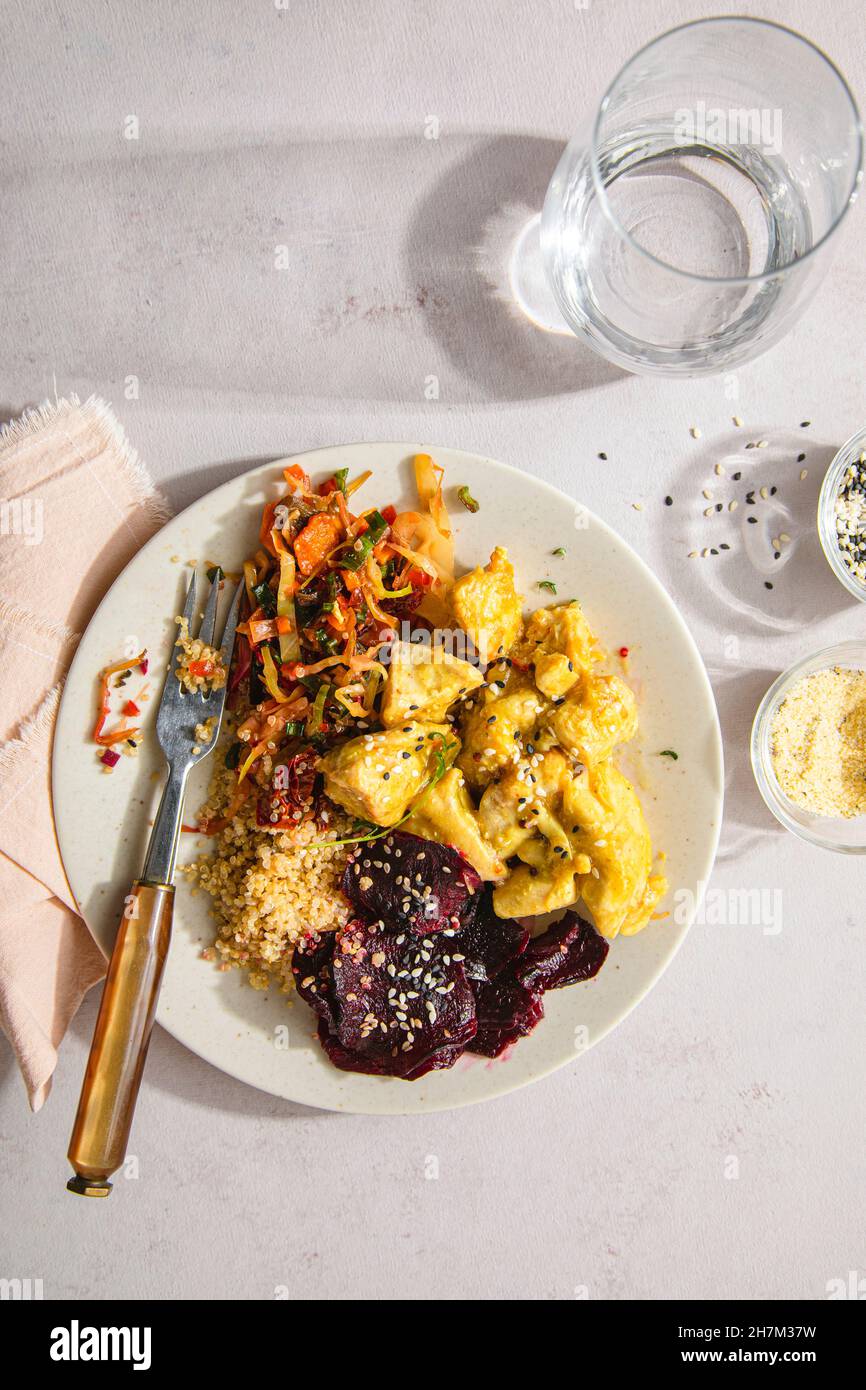 Pollo marinato fresco con quinoa e verdure in piatto sul tavolo Foto Stock