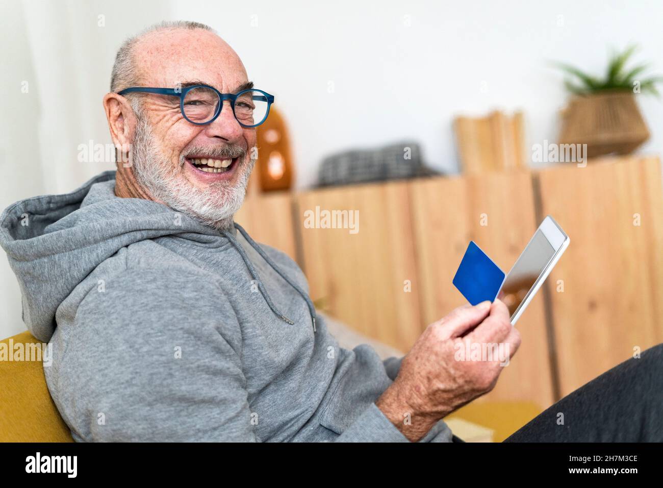 Uomo con carta di credito che utilizza un tablet PC a casa Foto Stock