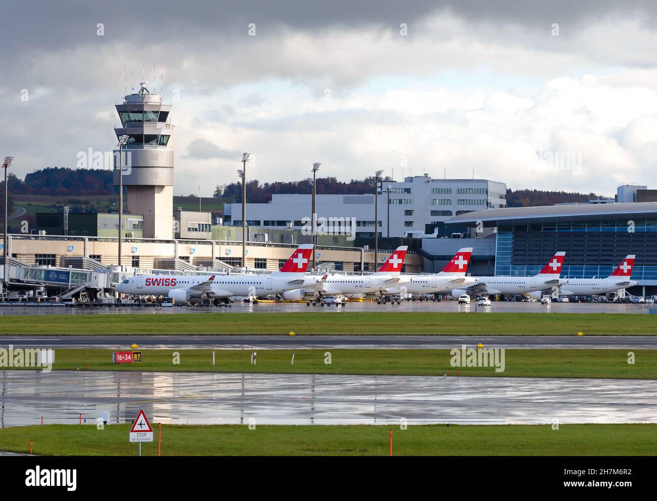 Aeroporto di Zurigo ATC e terminal con velivolo Swiss Airlines parcheggiato in condizioni di pioggia. Torre di controllo del traffico aereo dell'Aeroporto di Kloten a Swizterland. Foto Stock