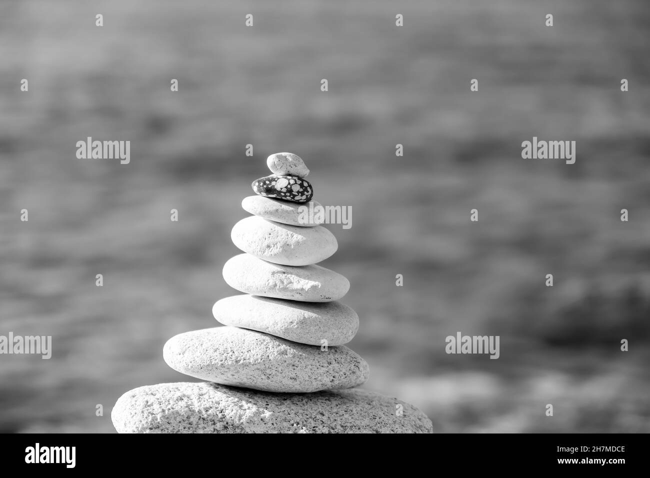 Pietre piramidali sulla riva in una giornata di sole sullo sfondo blu del mare. Buone vacanze. Spiaggia di ghiaia, mare calmo, destinazione di viaggio. Concetto di felice Foto Stock